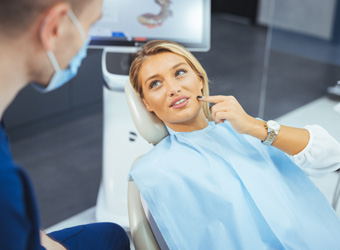 Patient in treatment chair talking to dentist