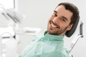 A smiling male patient sitting in a dental clinic