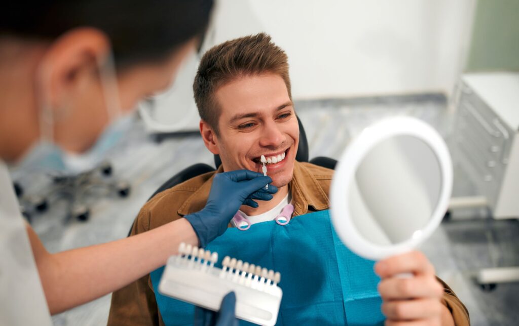 A man at the dentist selecting a shade of veneer.