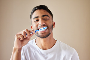 Man in white shirt brushing his teeth