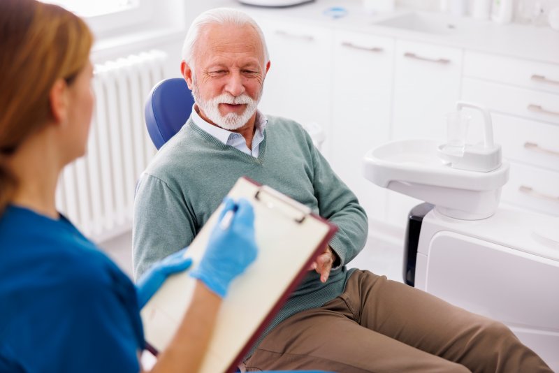 older man talking with dentist about full mouth reconstruction