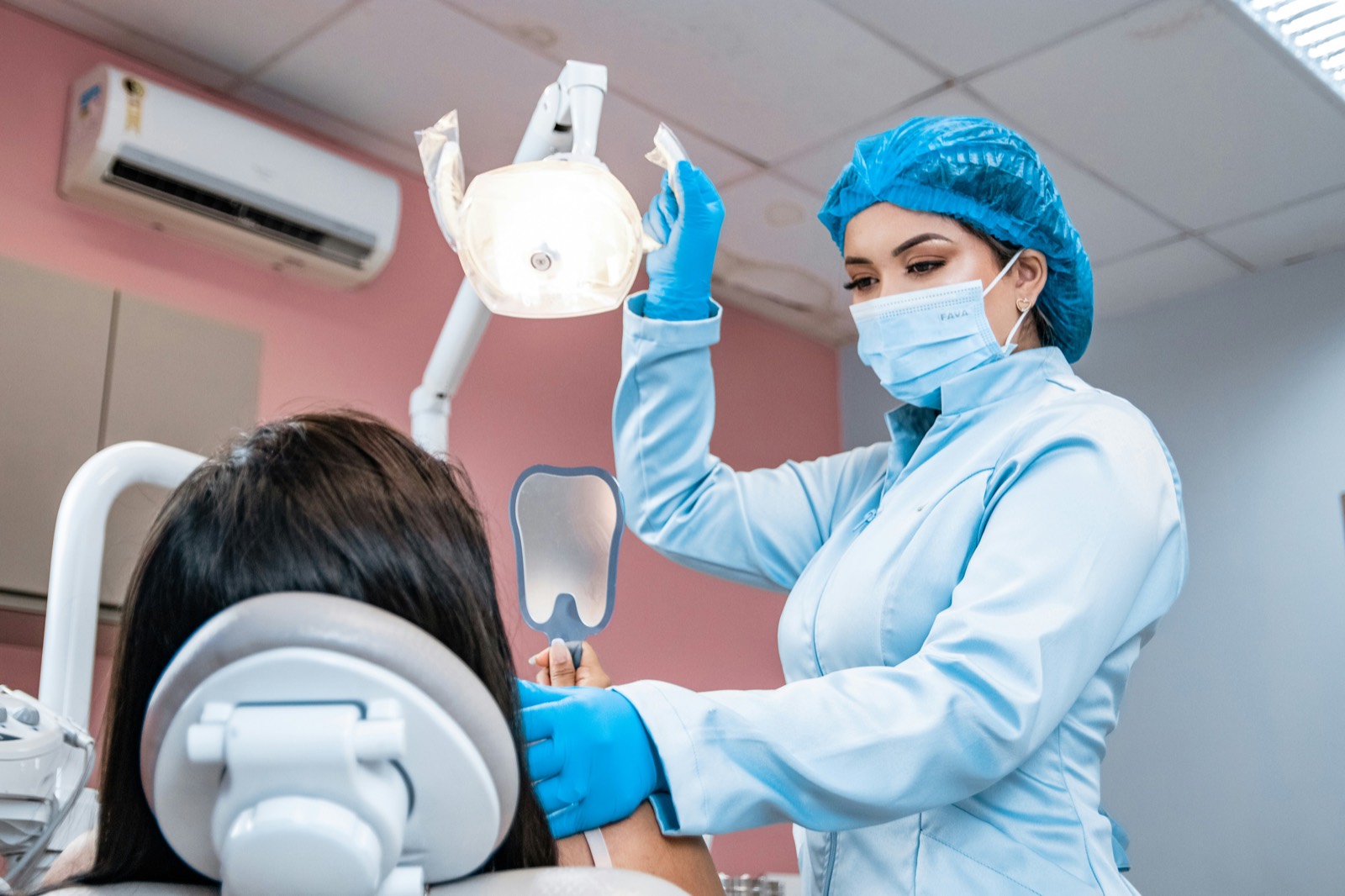 Dental assistant adjusting the overhead light for a patient in the chair