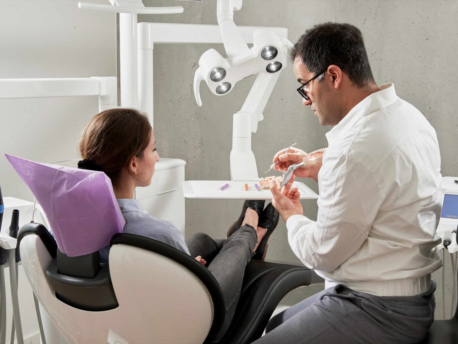 Dentist reviewing a dental model with a patient seated in the treatment chair